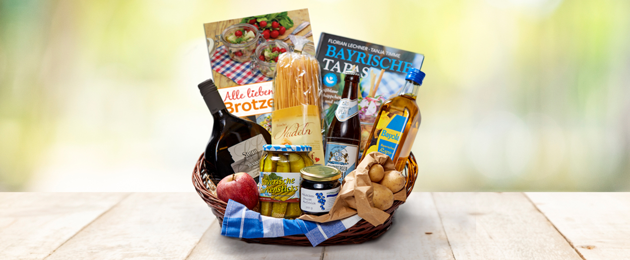 Ein Geschenkkorb mit bayerischen Spezialitäten, einschließlich Lebensmitteln, Getränken und Kochbüchern.