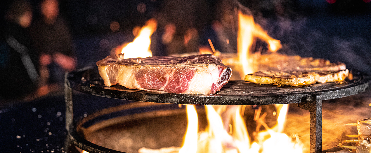 Saftige Steaks brutzeln über einem offenen Feuer, ideal für das Wintergrillen mit Freunden und Familie.