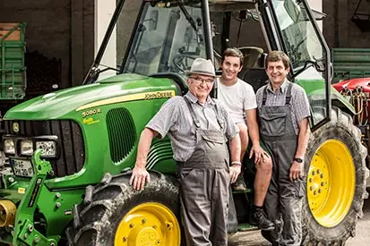 Foto: 3 Generationen von Landwirten vor dem Traktor