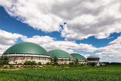 Biogasanlage mit großen, grünen Gaskugeln vor einem Wolkenhimmel, symbolisiert die Arbeit von Unsere Bayerischen Bauern.