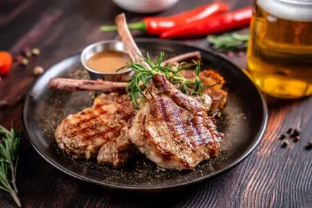 Gebratene Lammkoteletts mit Rosmarin und Bratensoße auf einem Teller