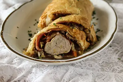 Schweinefilet im Blätterteig, gefüllt mit Gemüse und Schinken, angerichtet auf einer eleganten Servierplatte.