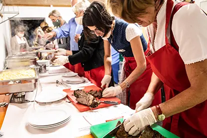 Freiwillige schneiden und servieren Essen bei einer Gemeinschaftsveranstaltung in einer festlichen, freundlichen Atmosphäre.