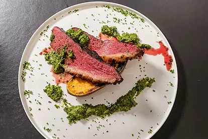 Gegrillter Tafelspitz auf Süßkartoffeln, serviert mit bayerischer Chimichurri und frischen Kräutern.