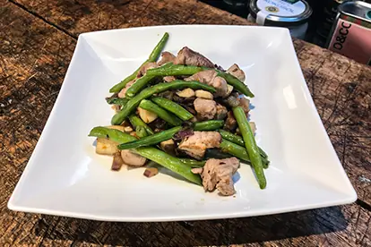 Vietnamesischer Bohneneintopf mit Schweinenacken, grüne Bohnen und zartem Fleisch auf weißem Teller angerichtet.