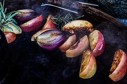 Geräucherte Apfel- und Zwiebelstücke mit frischem Rosmarin, ideal für die Zubereitung von Blumenkohl geräuchert.