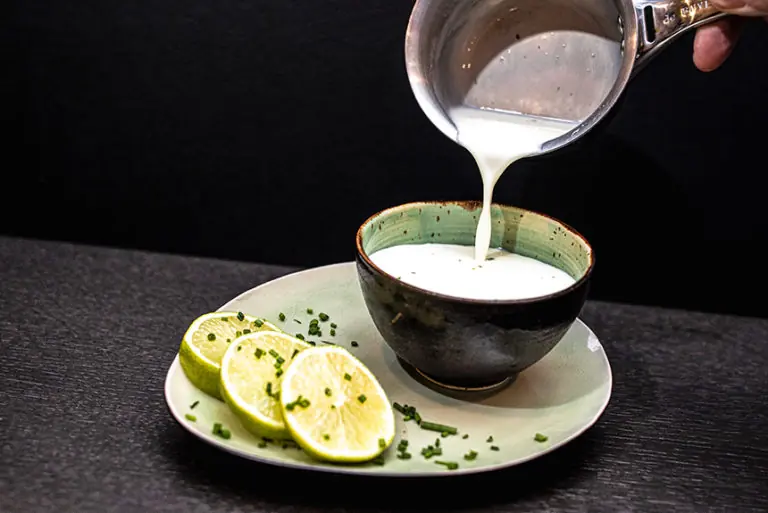 Frischer Joghurt wird in eine Schüssel gegossen, begleitet von Limettenscheiben und Schnittlauch im Milchworkshop.