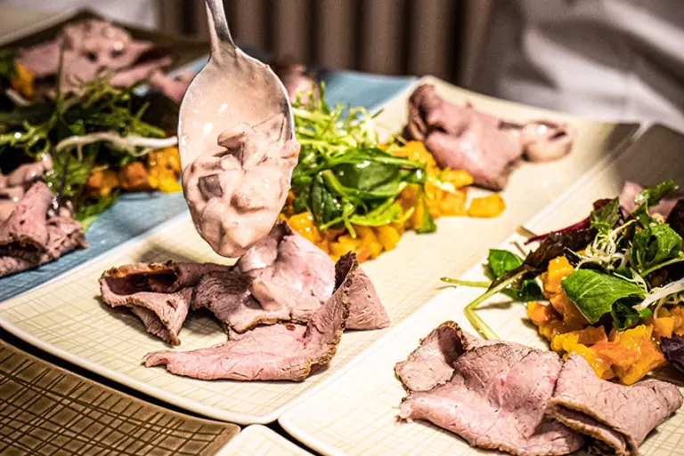 Zartes Rinderfilet wird mit einer cremigen Sauce und frischem Salat im Milchworkshop angerichtet.