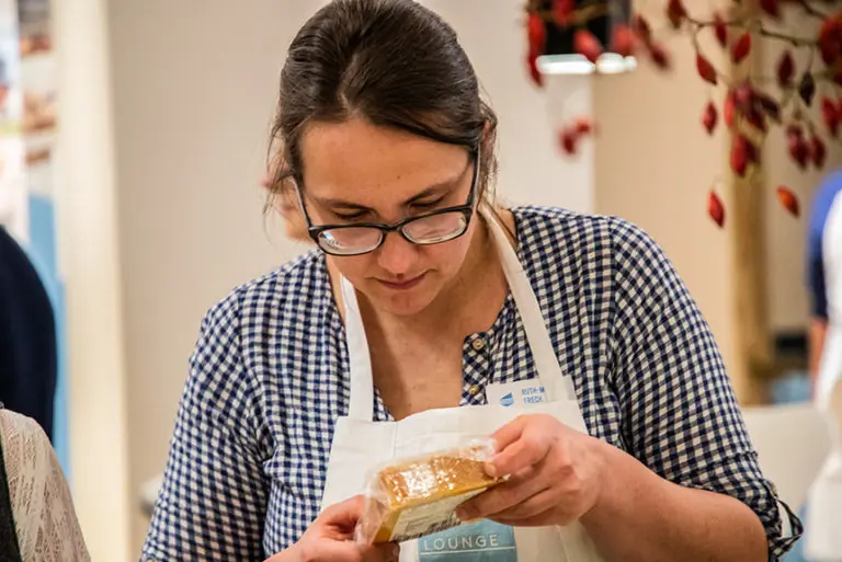 Teilnehmerin im Milchworkshop prüft aufmerksam eine Zutat in der Küche.