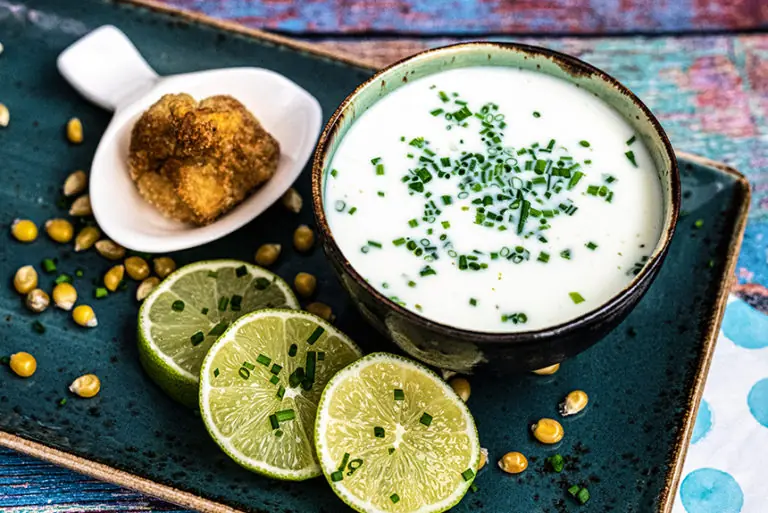Cremige Suppe mit frischen Kräutern, Limettenscheiben und einem knusprigen Snack, präsentiert im Milchworkshop.