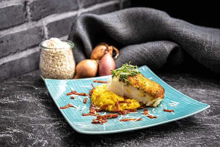 Ein Teller mit gebratenem Fisch, cremigem Risotto und frischen Kräutern, präsentiert im Milchworkshop-Kontext.