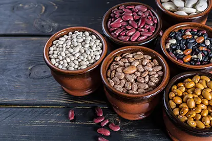 Bunte Hülsenfrüchte in Tontöpfen präsentieren die Vielfalt und Nährstoffe dieser modernen Superfood-Kulturpflanze.