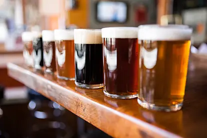 Eine Reihe von verschiedenen Biersorten in Gläsern auf einer Theke, ideal für Hopfen Bier-Fans.