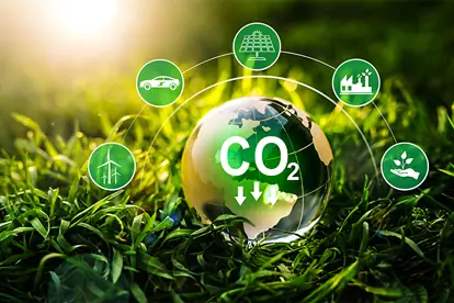 Ein Globus mit CO2-Reduktionssymbolen, umgeben von Icons für erneuerbare Energien und nachhaltige Praktiken.