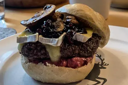 Saftiger Wildburger mit Käse, Pilzen und Preiselbeeren auf einem frischen Brötchen, serviert im Kreuthof.