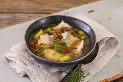 Herzhaftes Kartoffelgulasch in einer Schale, garniert mit frischen Kräutern und serviert auf einem rustikalen Tisch.
