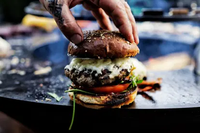 Ein saftiger Bacon-Cheeseburger mit geschmolzenem Käse, frischen Tomaten und einem handgemachten Brötchen.