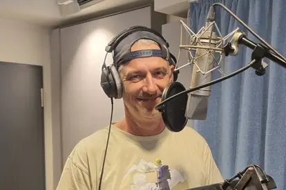 Ein Sprecher im Tonstudio mit Mikrofon und Kopfhörern, bereit für die Aufnahme eines Radiospots.
