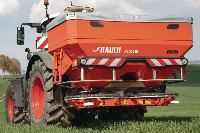 Ein Rauch AXIS Düngerstreuer auf einem Feld, der moderne Agrartechnik zur effizienten Düngung demonstriert.