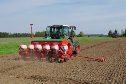 Ein moderner Traktor mit einer präzisen Sämaschine bearbeitet ein Feld im Bereich Agrartechnik.