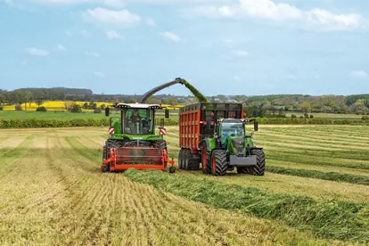 Zwei moderne Landmaschinen in einem Feld bei der Ernte, symbolisieren die Fortschritte in der Agrartechnik.