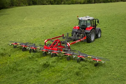 Ein roter Traktor bearbeitet ein grünes Feld mit einer innovativen Agrartechnik zur Grasernte.