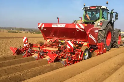 Ein roter Grimme Pflug bearbeitet ein Feld, symbolisiert moderne Agrartechnik in der Landwirtschaft.