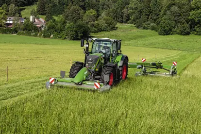 Ein Traktor mit Mähwerk mäht Gras auf einem Feld, demonstrierend moderne Agrartechnik in der Landwirtschaft.