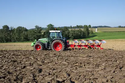 Ein Traktor mit Pflug bearbeitet ein Feld, symbolisiert moderne Agrartechnik in der Landwirtschaft.