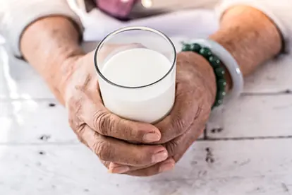 Eine Hand hält ein Glas Milch, das die Frage aufwirft, ob Milch gesund ist.