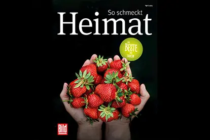 Frische Erdbeeren in Händen, symbolisieren Heimat und regionale Produkte auf einer Werbeanzeige.
