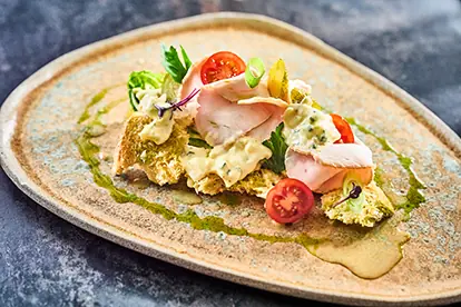 Putenbraten mit frischem Gemüse, Tomaten und einer cremigen Sauce auf knusprigem Brot serviert.